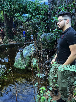 Ilyes standing by a pond in a jungle setting